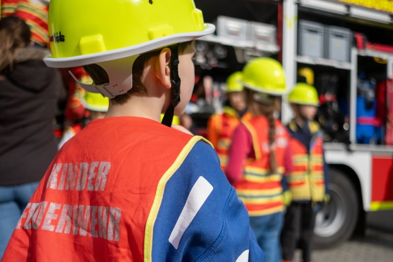 Kinder in gelben Helmen und roten Westen mit der Aufschrift 
